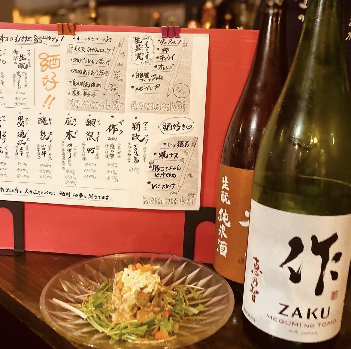 手書きの日本酒メニューと日本酒の瓶、一品料理